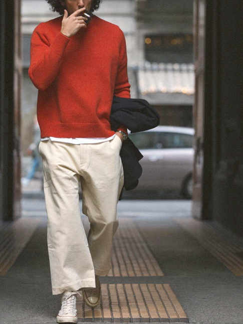 Pantalon large beige court sur la cheville + tee-shirt blanc dpassant d'un pull rouge col rond = le bon mix