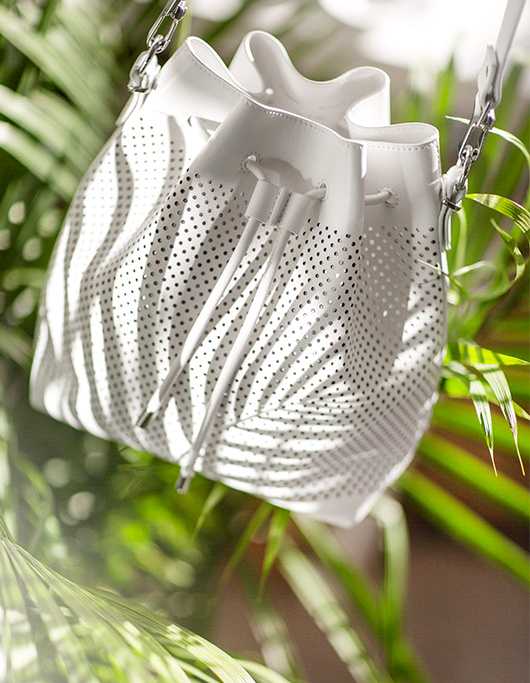 Avec sa forme seau et son cuir blanc perfor�, ce sac printanier a tout bon !