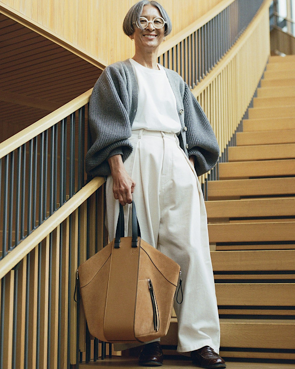 Femme de plus de 60 ans portant un pantalon taille haute fluide, un top blanc et un cardigan gris ample