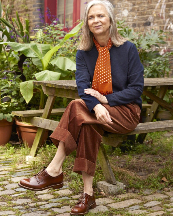 Femme de 70 ans portant une veste légère beige, un pantalon ample et un foulard dans une tenue printanière confortable