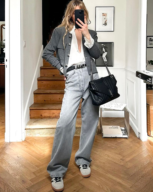 Jean gris délavé ample porté avec une blouse blanche, une veste grise et un sac noir matelassé