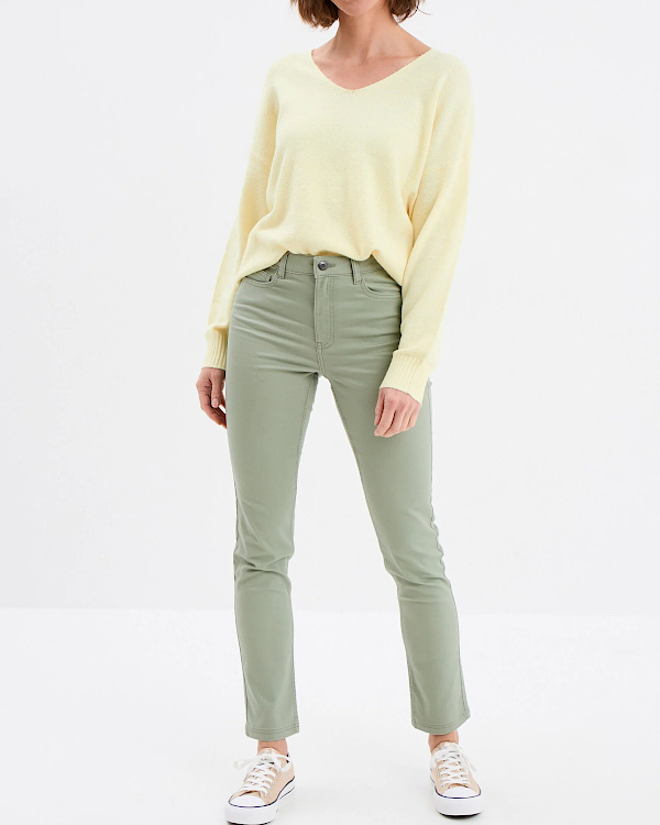 Slim vert d'eau porté avec un pull jaune pastel à col V et des baskets basses claires dans un look décontracté lumineux