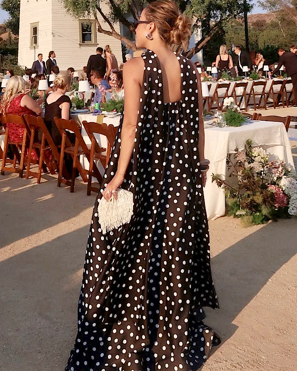 Robe ajustée à pois blancs portée lors d'une réception élégante en extérieur
