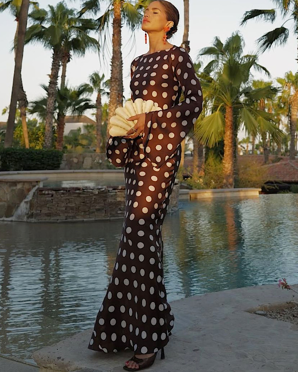 Invitée de mariage portant une robe noire à pois blancs et une pochette texturée
