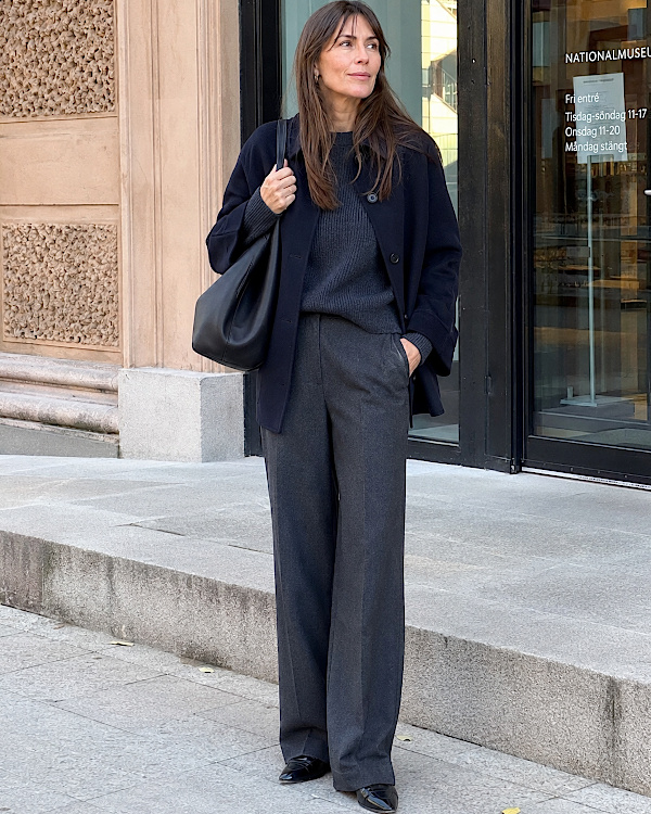 Femme en ensemble bleu marine à la coupe ample devant un musée à Stockholm