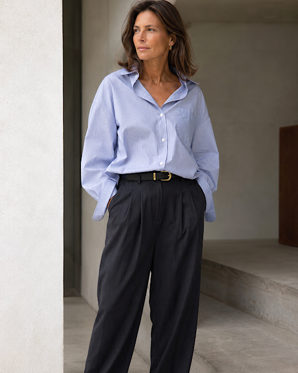 Femme brune portant une chemise oversize bleu clair rentrée dans un pantalon noir large