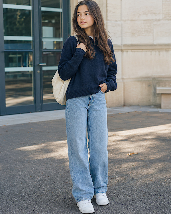 Adolescente brune en pull marine et jean large pour une tenue de rentrée au collège