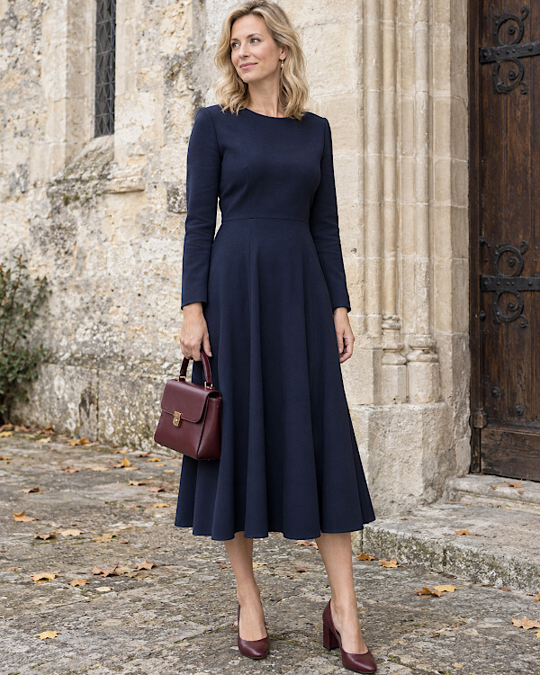 Femme en robe midi bleu marine avec sac et escarpins bordeaux