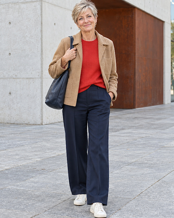 Femme blonde en blazer camel, pull rouge, pantalon large marine et baskets blanches