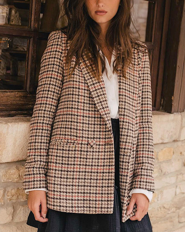 Femme portant un blazer à carreaux beige et marron sur une chemise blanche