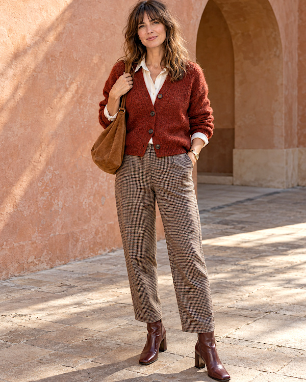 Femme en cardigan rouille, chemise blanche, pantalon à carreaux et bottines marron